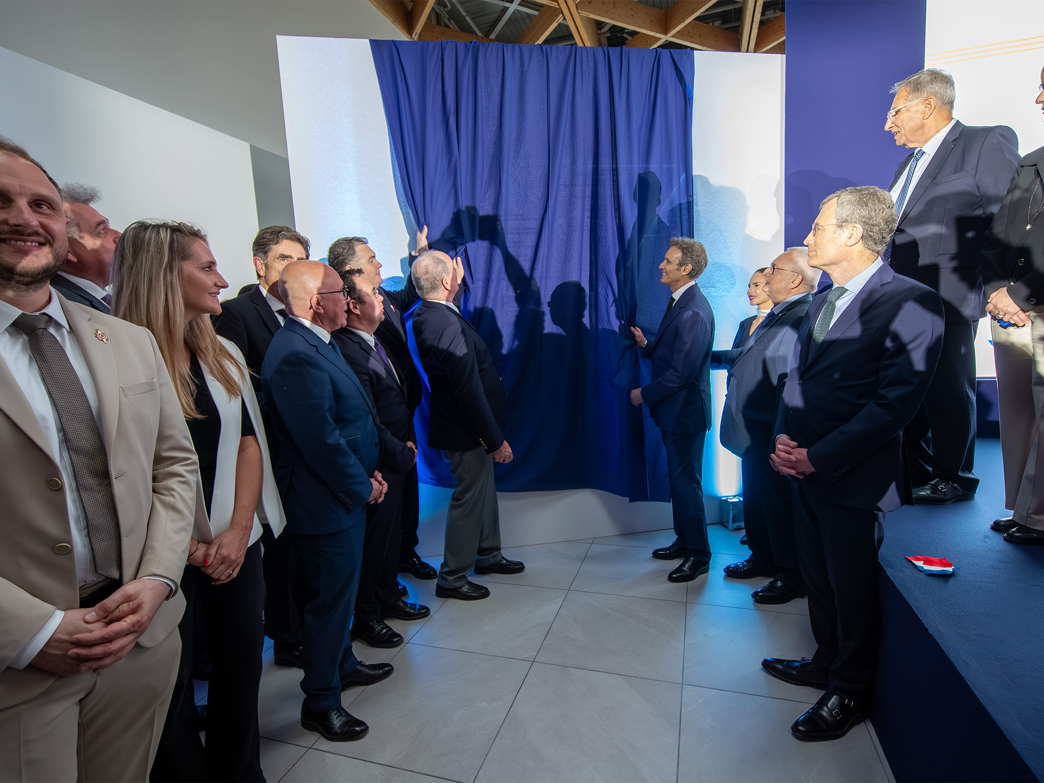 Groupe de personnalités posant devant la plaque commémorative de l'inauguration de l'extension de l'aéroport de Nice