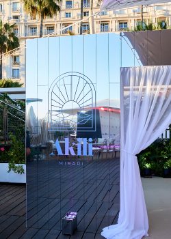 Tunnel immersif sur mesure réalisé par AUCOP pour la soirée Akili Mirari au Festival de Cannes 2026 : voilages blancs drapés et panneaux miroirs sur la plage Croisette Beach, éclairage Smart BAT mauve
