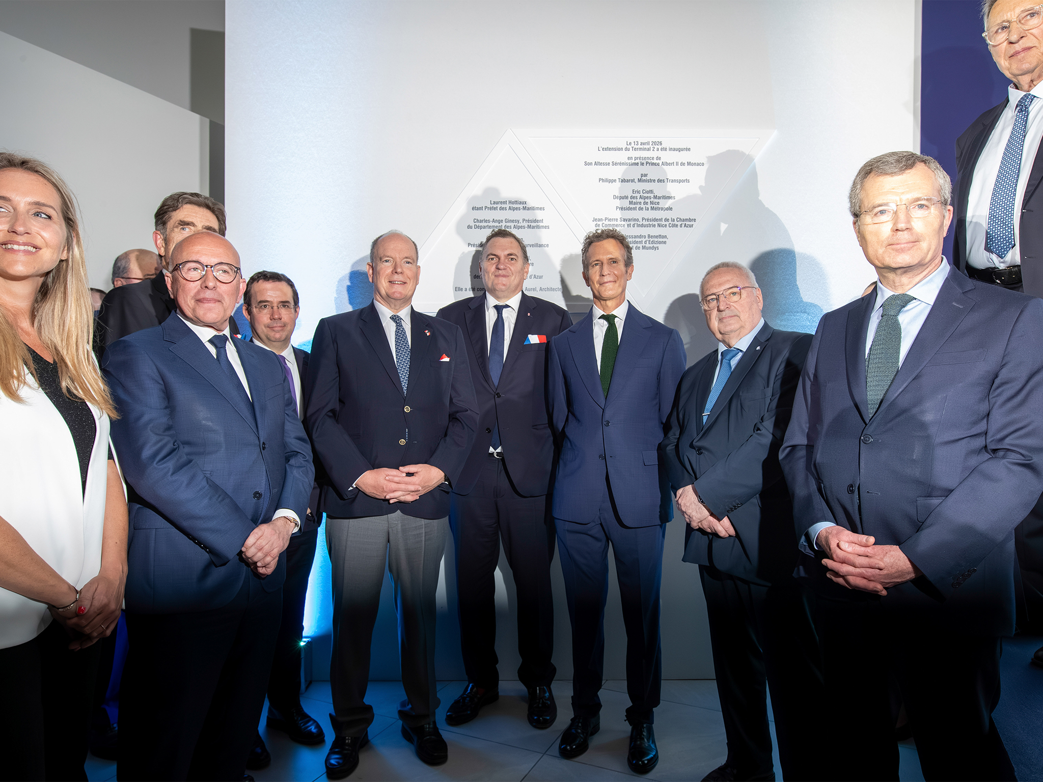Groupe de personnalités posant devant la plaque commémorative de l'inauguration de l'extension de l'aéroport de nice