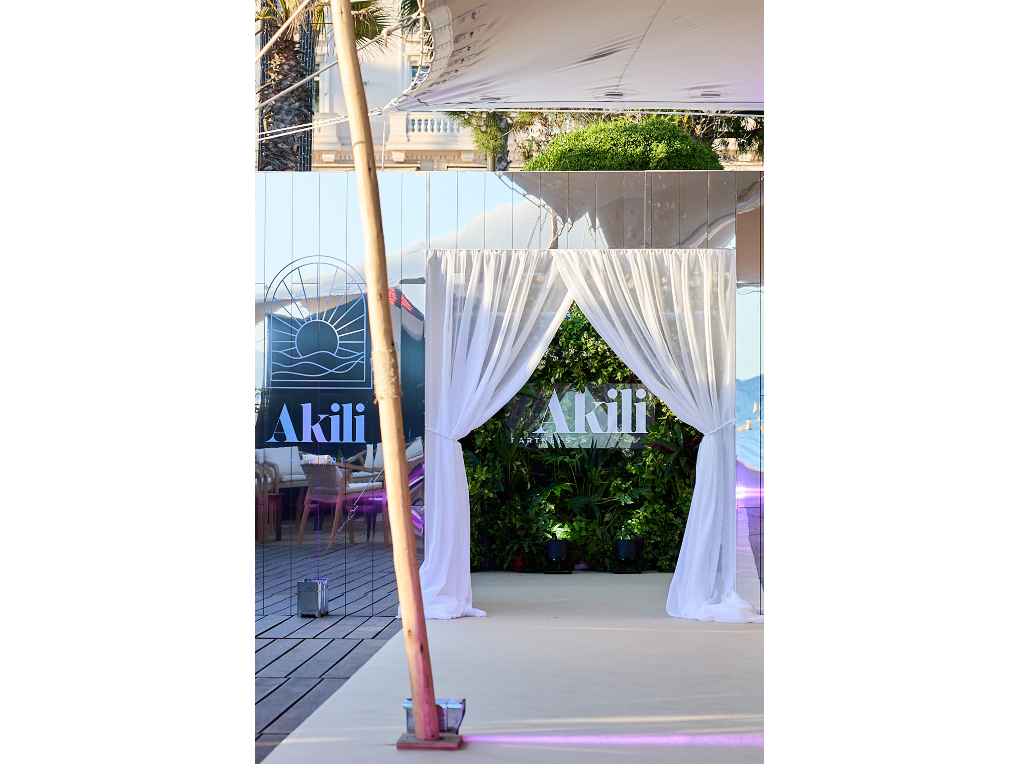 Tunnel immersif sur mesure réalisé par AUCOP pour la soirée Akili Mirari au Festival de Cannes 2026 : panneaux miroirs et voilages blancs drapés sur la plage Croisette Beach, éclairage Smart BAT mauve