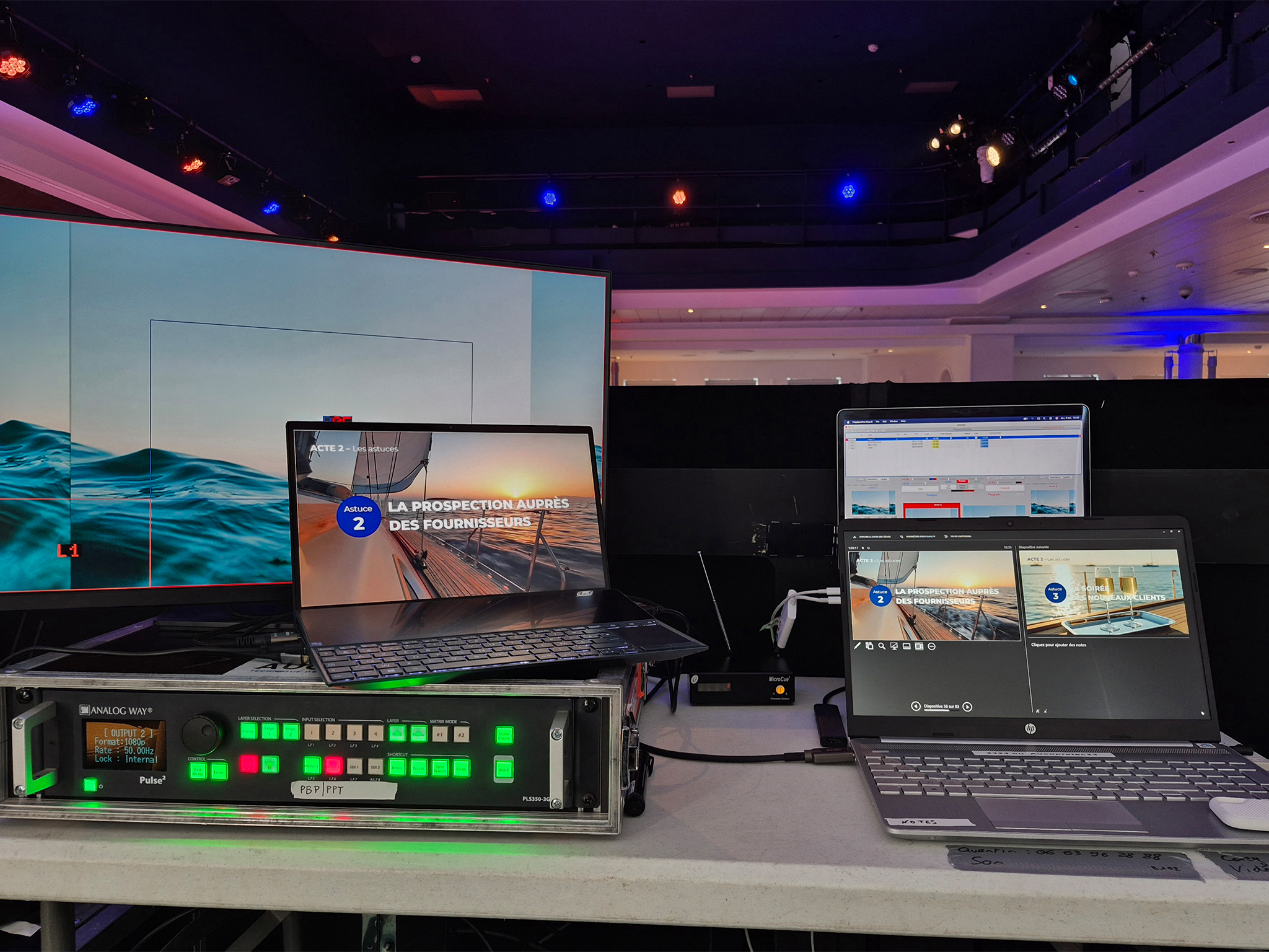 Régie vidéo Analog Way Pulse² installée par AUCOP à bord du Club Med 2 pour la convention corporate au port de Nice : laptops de contrôle, écran large en fond, lumières d'ambiance bleues et rouges au plafond — production audiovisuelle embarquée AUCOP, Côte d'Azur