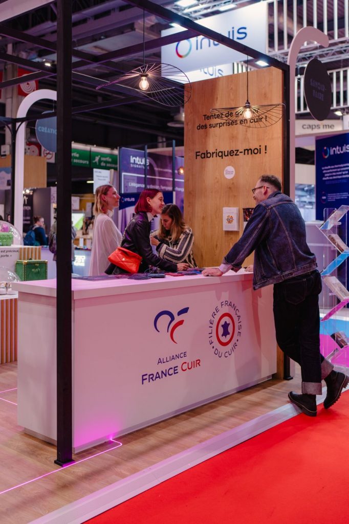 Stand Made in Cuir - desk d'accueil - MIF Expo 2025 Espace Made in Cuir MIF Expo 2025 - stand sur mesure Alliance France Cuir avec podiums bois et cloches de présentation, réalisé par Aucop Paris