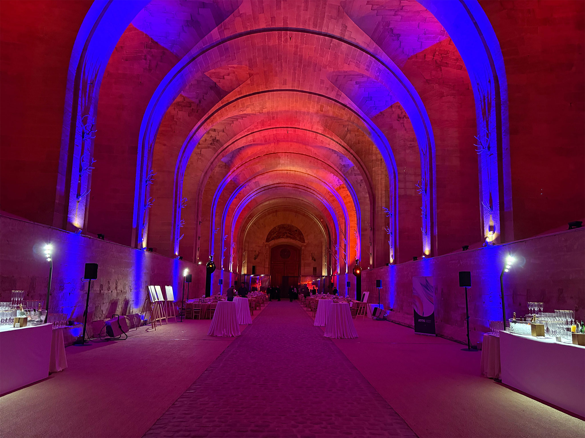 SUBLIMER LE PATRIMOINE PAR LA LUMIERE. Nef historique transformée en salle de gala avec mise en lumière bleue et orange par Aucop Paris pour Atos