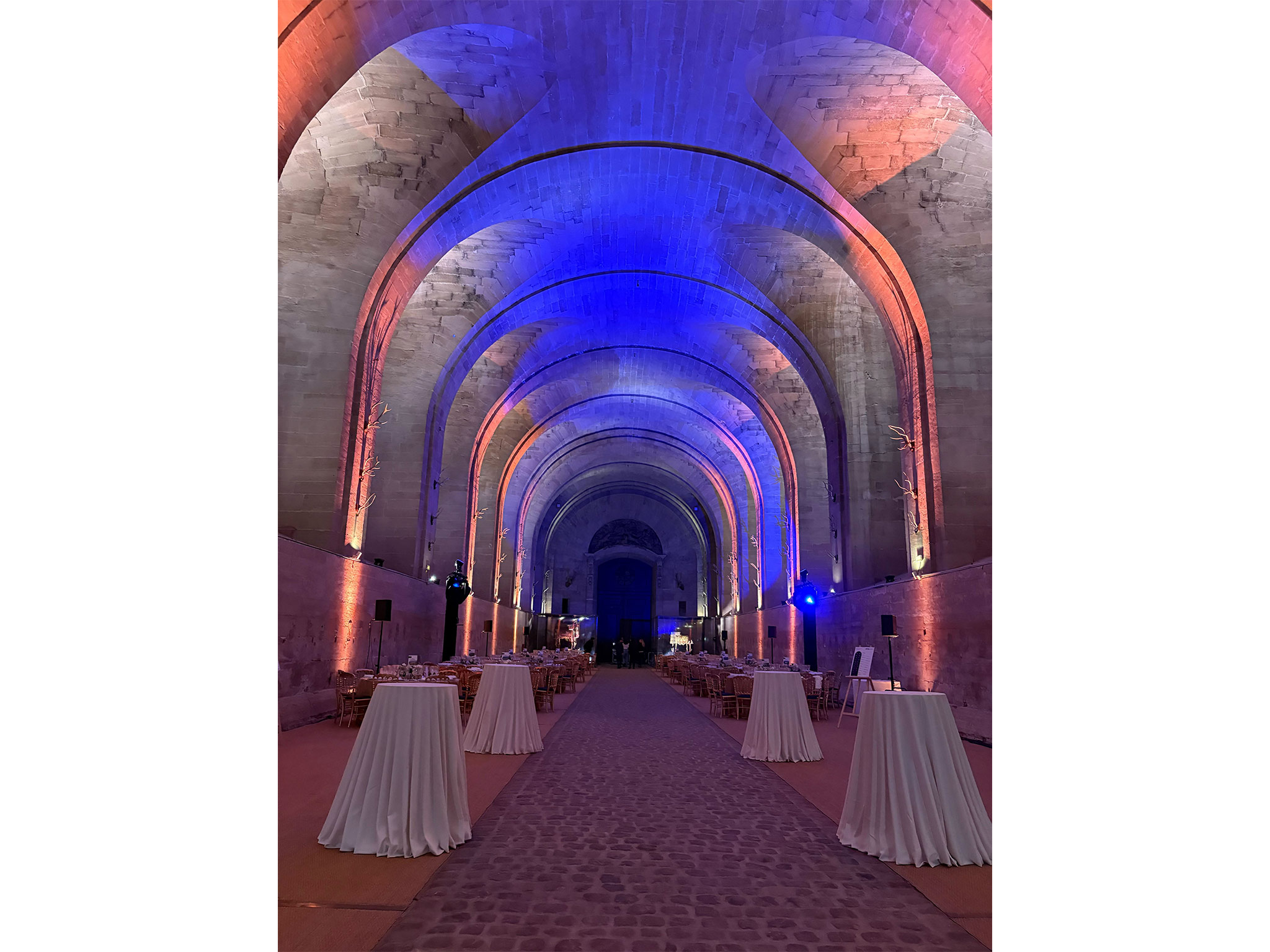 SUBLIMER LE PATRIMOINE PAR LA LUMIERE. Nef historique transformée en salle de gala avec mise en lumière bleue et rose par Aucop Paris pour Atos