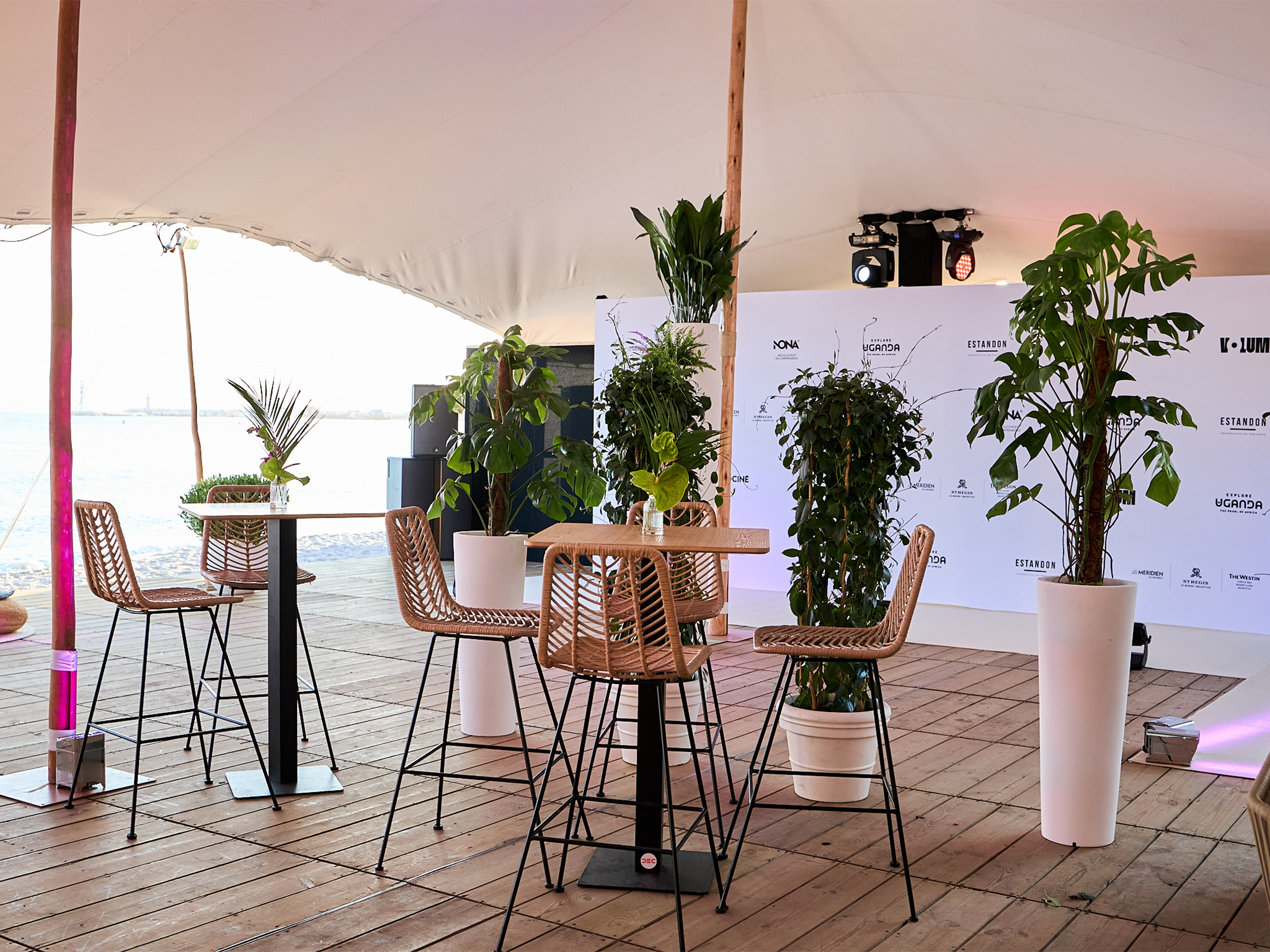 Photocall step-and-repeat sponsors de la soirée Akili Mirari au FIF Cannes 2026 : backdrop blanc avec logos Allociné, K-Lum, Explore Uganda, Estandon, Le Méridien, installé et éclairé par les équipes AUCOP