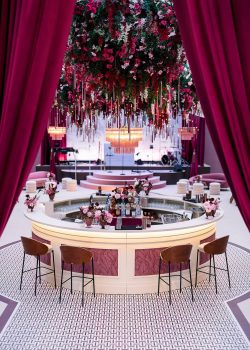aucop-bar-arrondi-sur-mesure-salle-soiree-mariage-hotel-cap-eden-roc-2026 Tables du dîner de mariage et lustre en cascade de cristal rose à l'Hôtel du Cap-Eden-Roc — chaises velours rose, centre de table floral, mise en lumière AUCOP