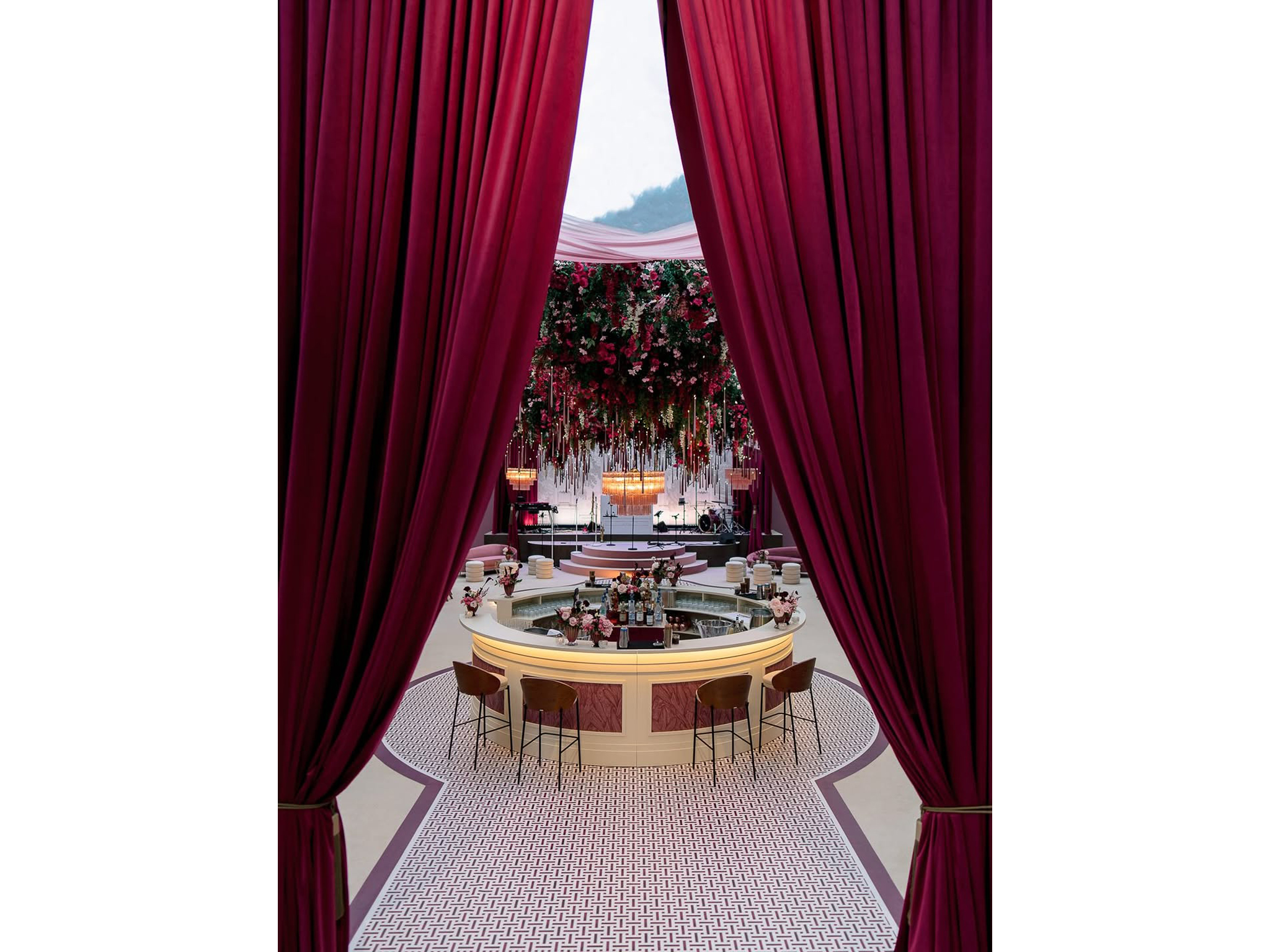 Entrée de la salle de réception avec rideaux velours bordeaux encadrant la vue sur le bar arrondi AUCOP et le plafond floral — mariage Angelina & Kelvin, Hôtel du Cap-Eden-Roc