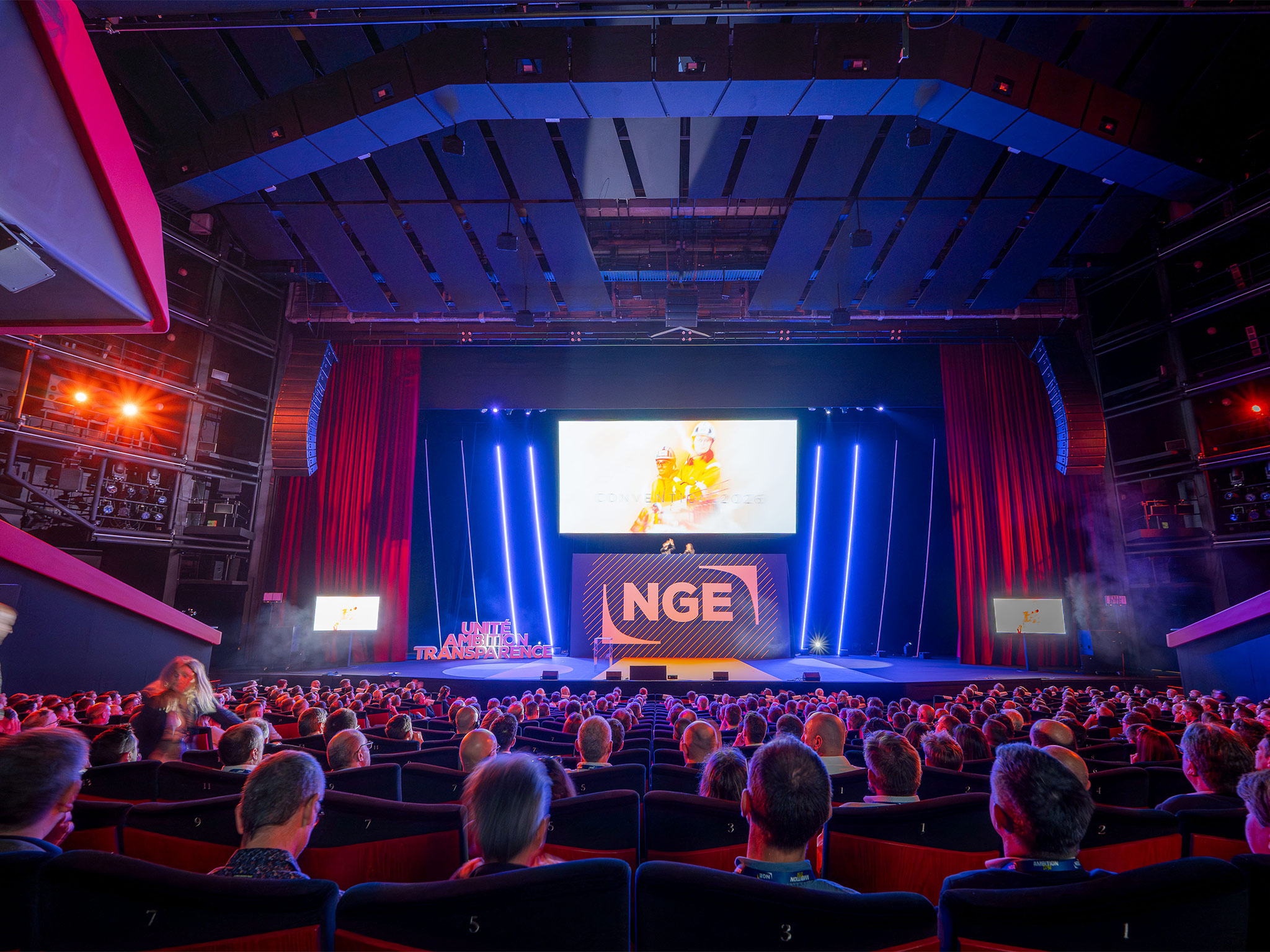 Auditorium du Palais des Festivals comble lors de la plénière NGE Ambition 2030 : fond de scène, logo NGE illuminé, vidéoprojection et mise en lumière signés AUCOP, plus de 1 000 collaborateurs en salle.