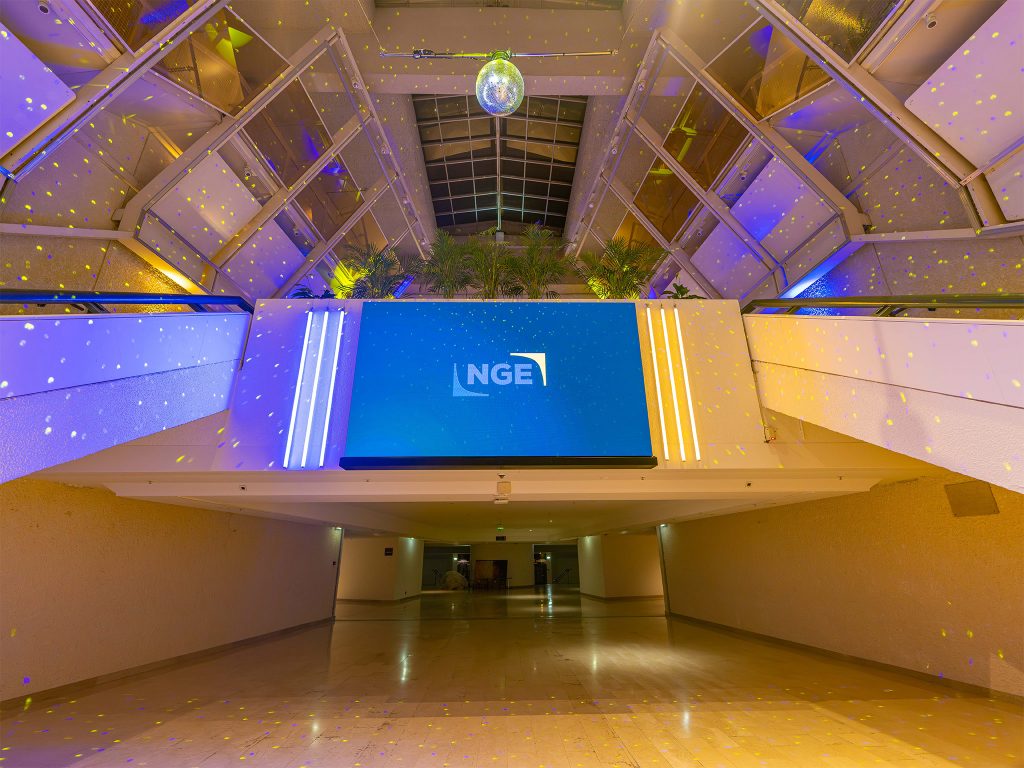 Salon des Ambassadeurs du Palais des Festivals transformé en club privé par AUCOP pour la soirée de la convention NGE Ambition 2030 : éclairages bleu et or, boule à facettes, écran LED NGE et scène DJ.