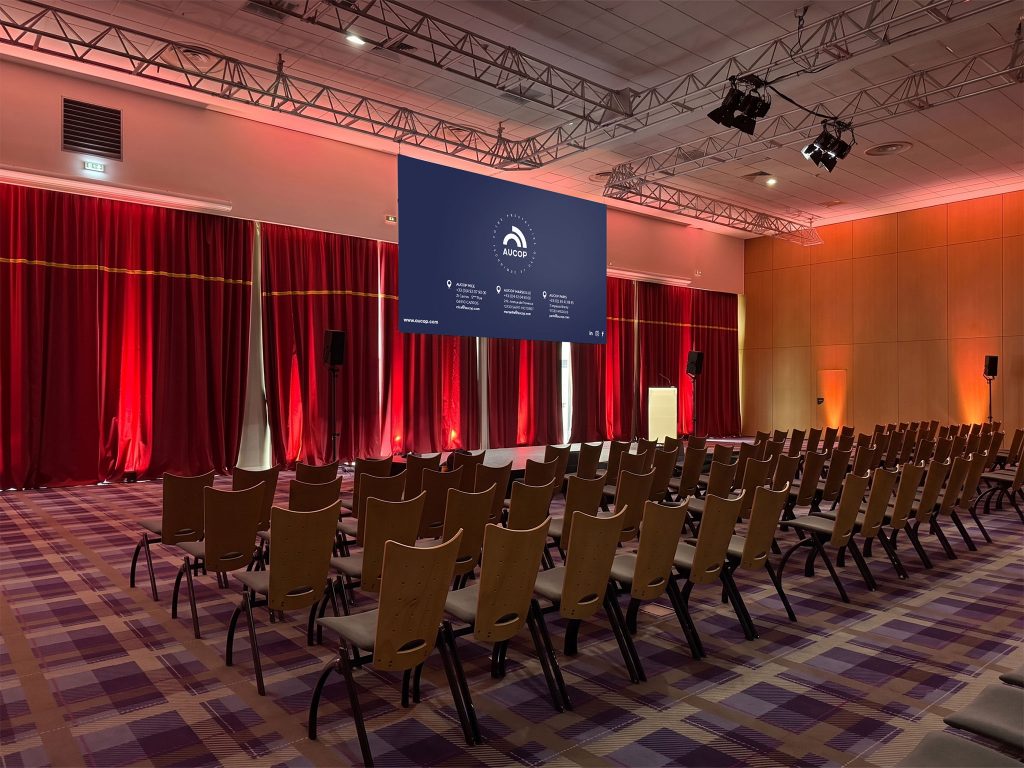 Vue panoramique de la salle du séminaire d'entreprise au Club Med Opio : éclairage d'ambiance PROLIGHTS SmartBat HEX, écran Stumpfl 16/9 et structure grill — dispositif audiovisuel AUCOP, Côte d'Azur