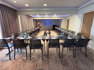 Salle de séminaire en configuration U au Radisson Blu de Nice, écran de vidéoprojection AUCOP en fond de salle et écrans de retour au centre.