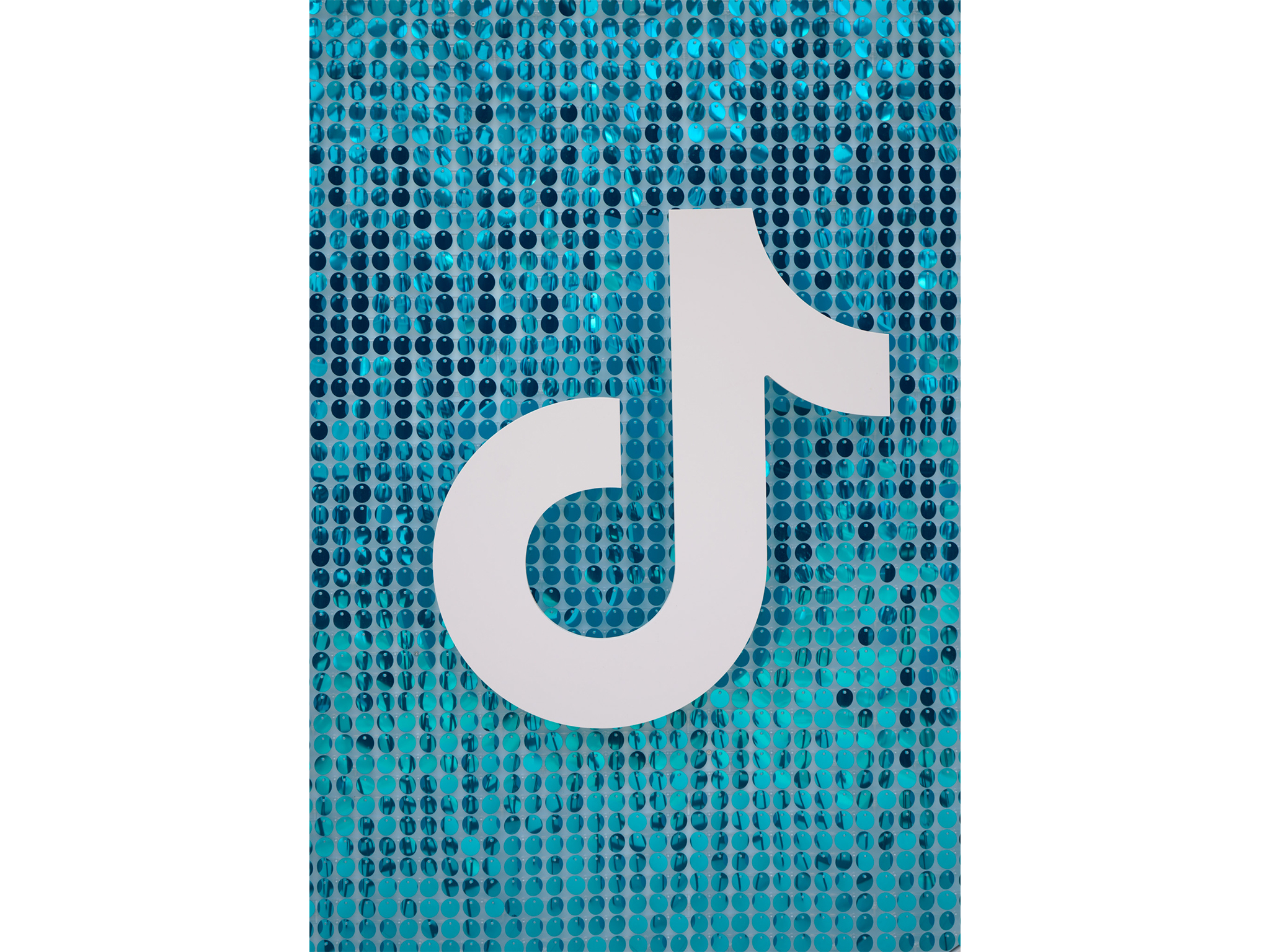 Gros plan sur le grand sparkle mural en perles de sequins bleu turquoise fabriqué sur-mesure par les ateliers AUCOP, orné du logo TikTok blanc sculpté en relief en Forex.