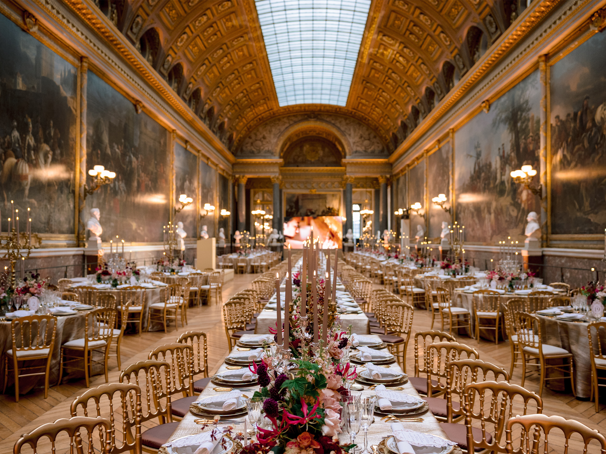 Tables dressées dans la Galerie des Batailles avec mur LED en fond, dîner caritatif American Friends of Versailles au Château de Versailles