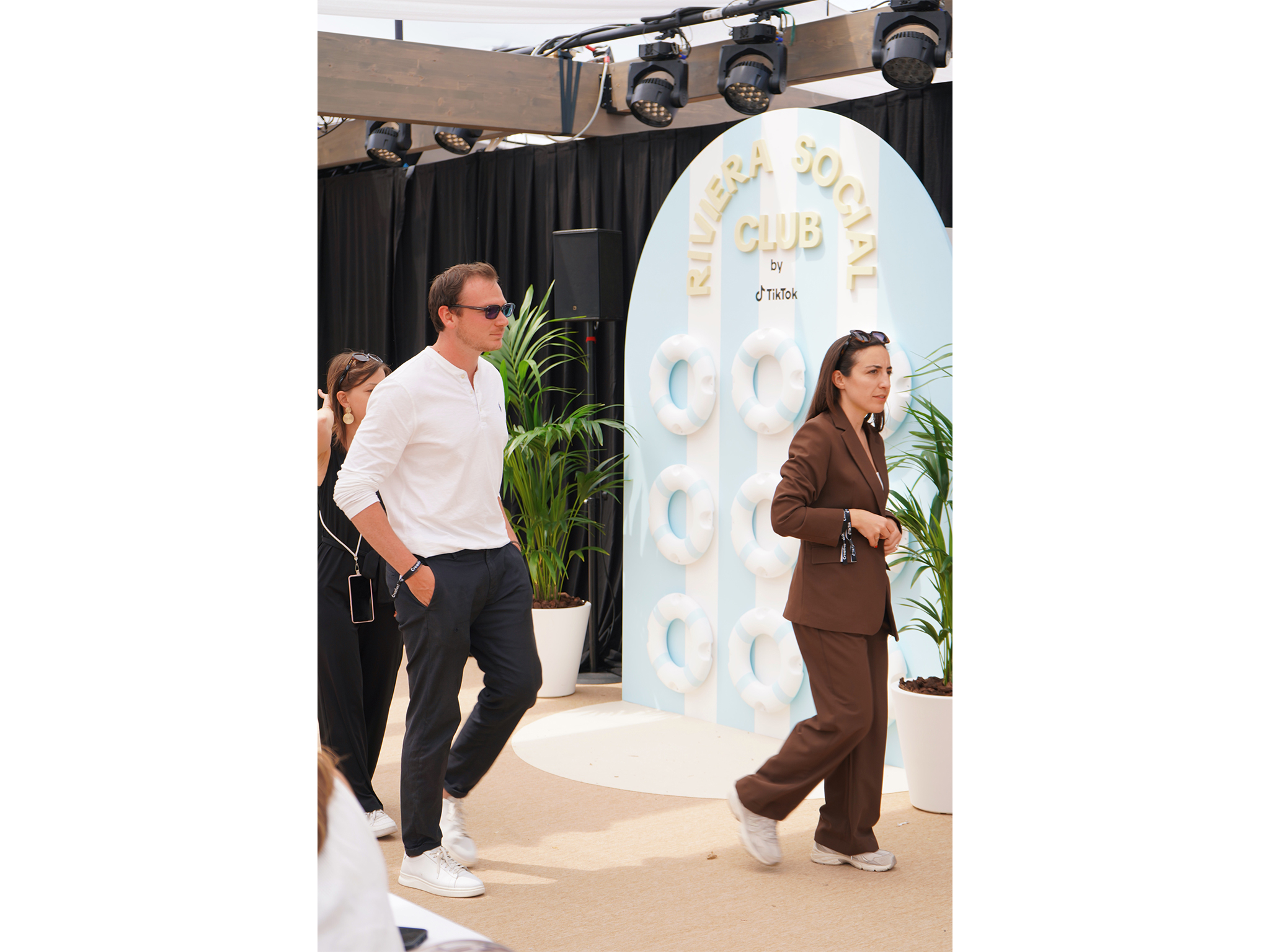 Invités et créateurs de contenu circulant à côté du photocall thématique à bouées et rayures "Riviera Social Club by TikTok", installé par AUCOP sur la Plage Vegaluna pendant le Festival de Cannes.