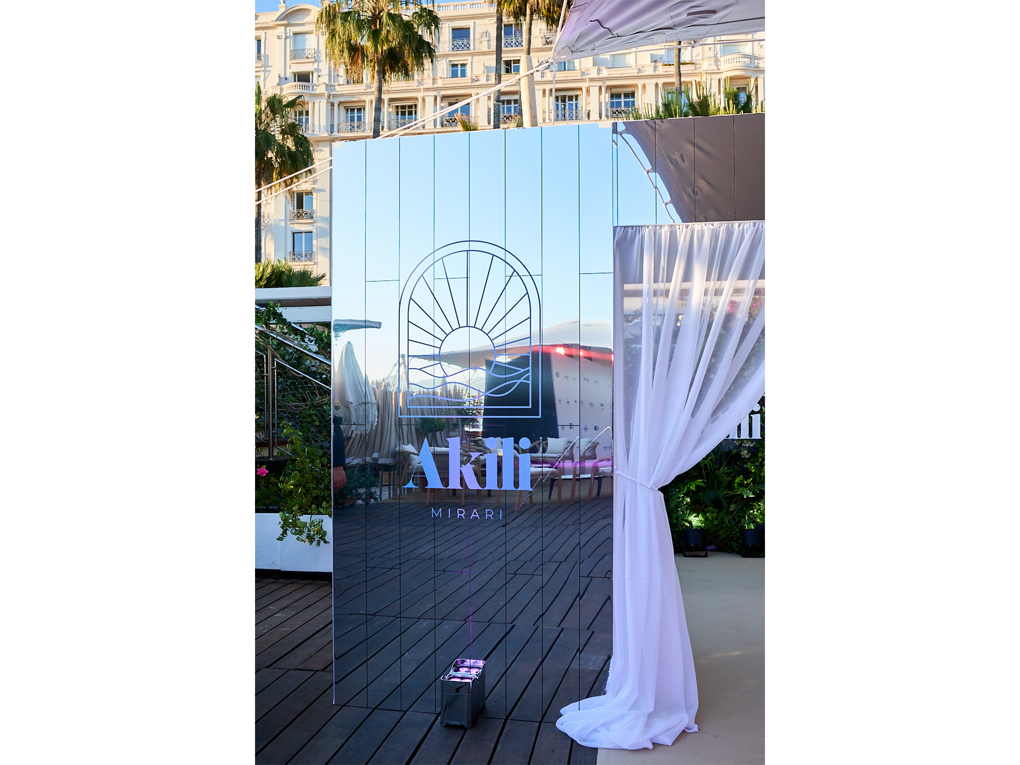 Tunnel immersif sur mesure réalisé par AUCOP pour la soirée Akili Mirari au Festival de Cannes 2026 : voilages blancs drapés et panneaux miroirs sur la plage Croisette Beach, éclairage Smart BAT mauve