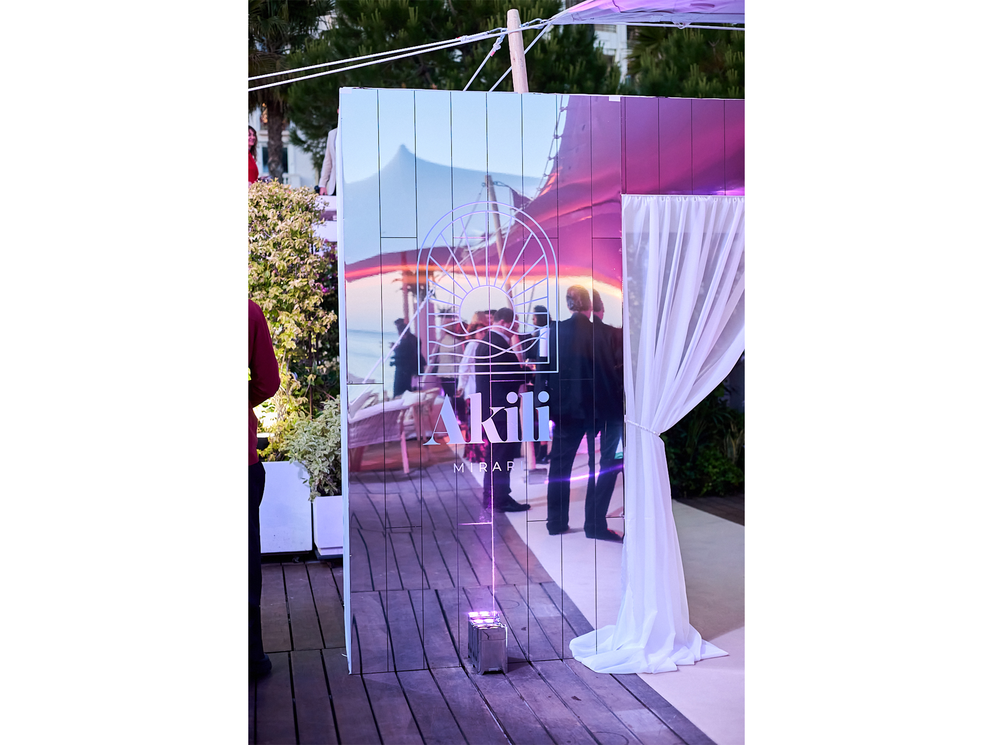 Tunnel immersif sur mesure réalisé par AUCOP pour la soirée Akili Mirari au Festival de Cannes 2026 : voilages blancs drapés et panneaux miroirs sur la plage Croisette Beach.