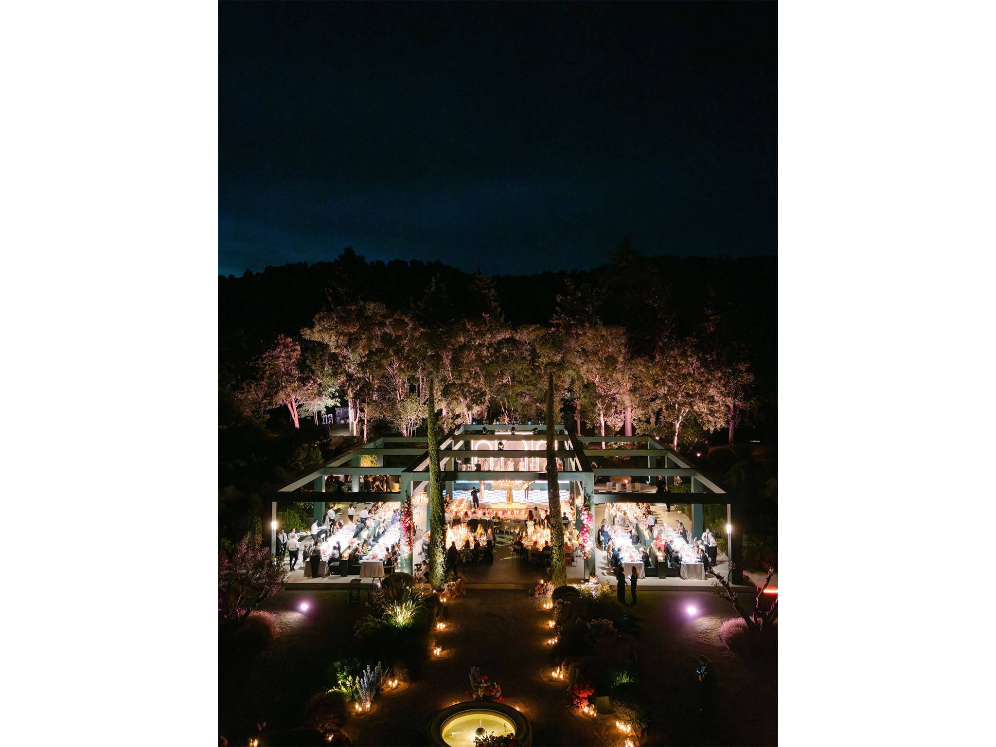 AUCOP - Vue aérienne nocturne du dîner de mariage sous la pergola-structure monumentale illuminée, longues tables, piste de danse damier centrale et arbres éclairés - scénographie White Eden Weddings, production AUCOP, Airelles Château d'Estoublon, Provence