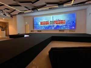 MISSION : DIMPOSSIBLE Vue d'ensemble de la salle de convention au World Trade Center Marseille Provence – installation audiovisuelle et scénographique AUCOP avec écran grand format, projecteurs asservis et chaises noires en configuration théâtre