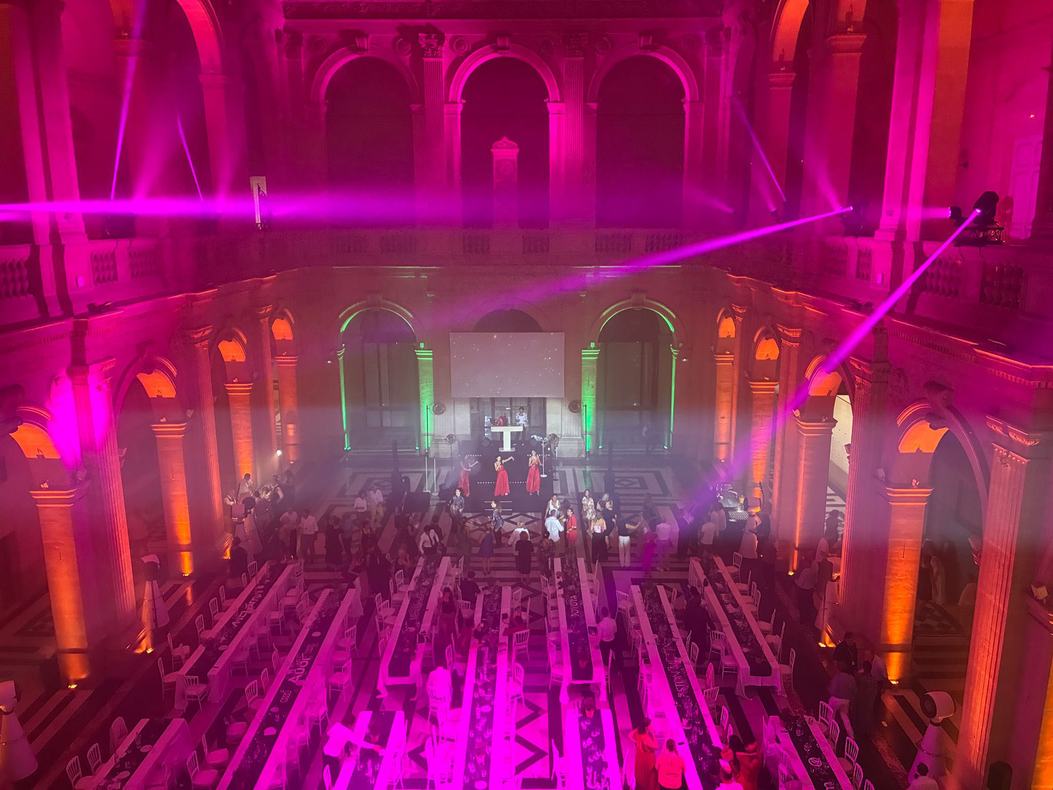 Soirée de gala au Palais de la Bourse à Marseille : faisceaux de lumière magenta, performance live sur scène et convives, mise en lumière et sonorisation AUCOP